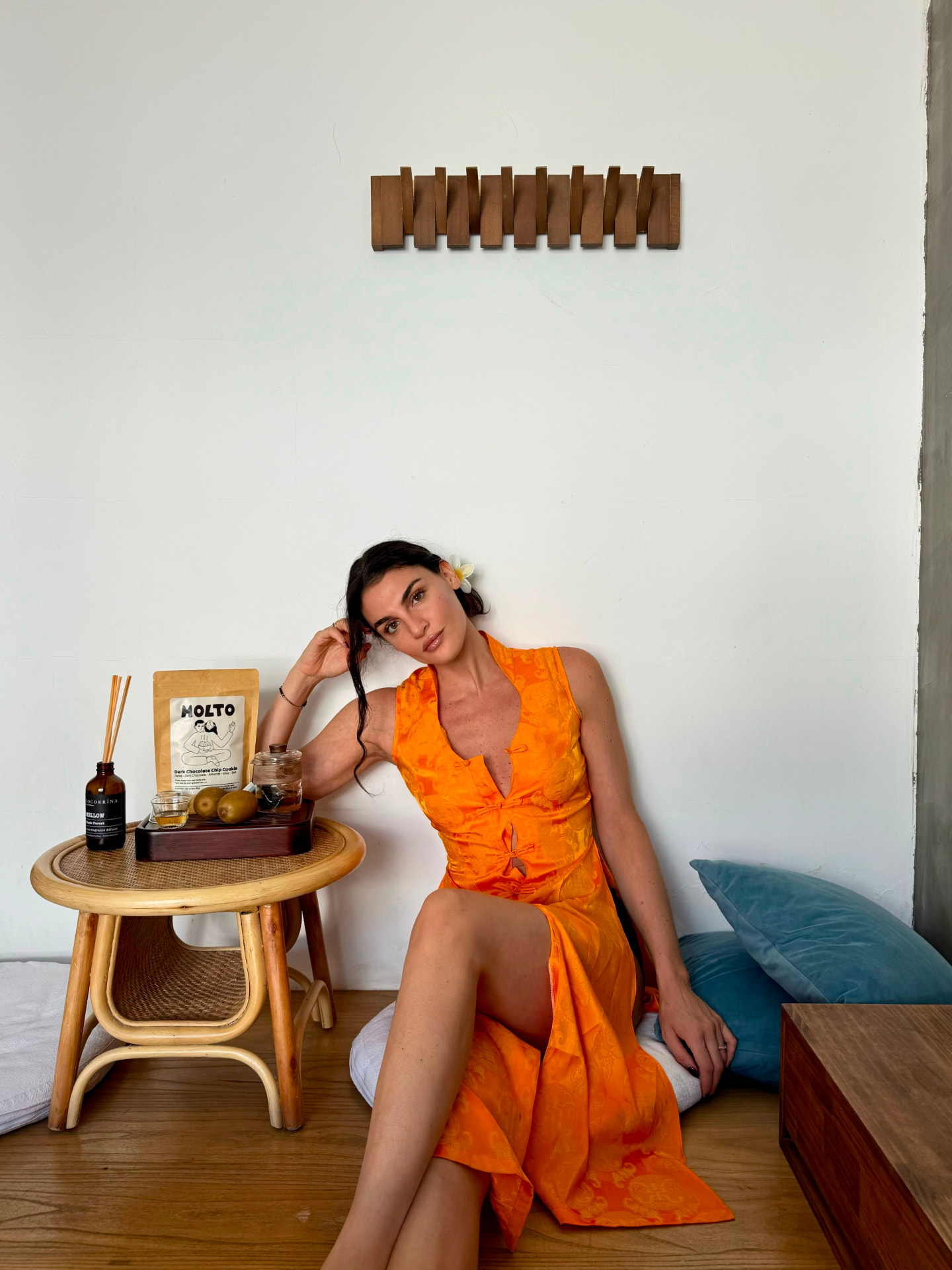 MOLTO cookie pouch beside a woman on a floor cushion with a reed diffuser and kiwis